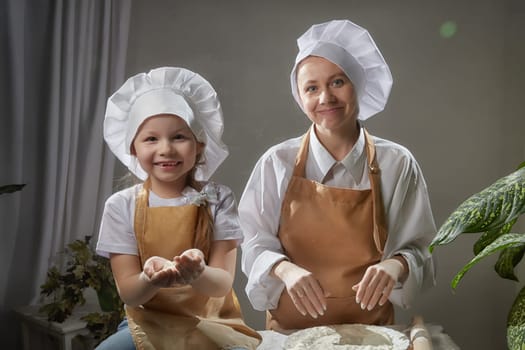 Cute oriental family with mother, daughter cooking in kitchen on Ramadan, Kurban-Bairam, Eid al-Adha. Funny family at cook photo shoot with flour. Easter