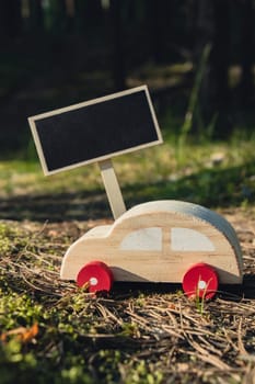 Empty blackboard with copy space Wooden toy car on greenery forest background. Eco-car concept World car free day electric vehicle environment automobile transportation electric vehicle. Hybrid electric. Sustainable engine. Zero CO2 emission for natural awareness and green environment pollution concept