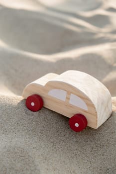 Wooden toy car on sandy beach background. Eco-friendly travel, reduce carbon footprints, environmental impact, Conscious Traveler, Environmentally Friendly, responsible traveler Eco-car concept World car free day. Roadtrip local travel