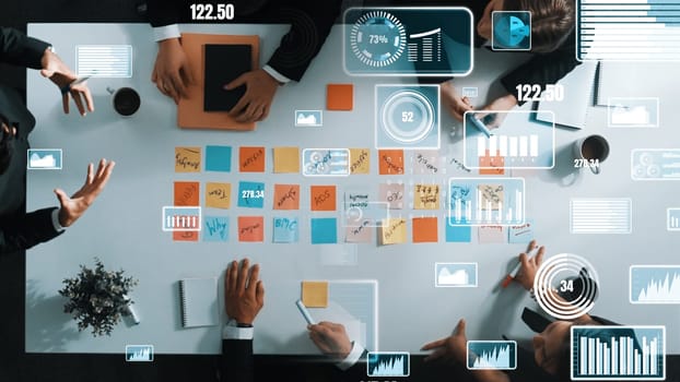Top down aerial view of smart business people sharing marketing idea by writing sticky notes and placed on meeting table with data analyst holographic or hologram of financial statistic. Directorate.
