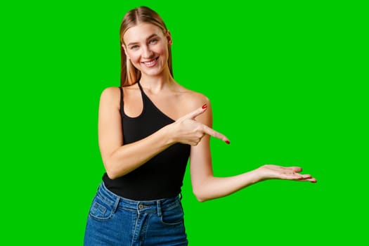 Young Woman Pointing at Something against green background in studio