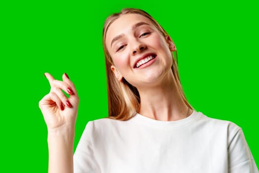 Young Woman Pointing Up Against Green Background in Studio