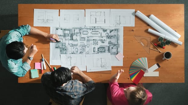 Group of people looking at blueprint while brainstorming idea. Top view of engineer team looking and planning house construction by using blueprint. Engineer hold paper while point at plan. Symposium.