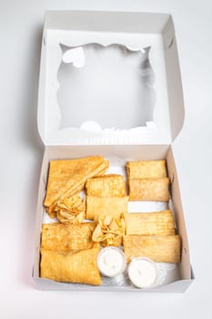 12 small pancakes with sweet and savory fillings in a white box. Options include cheese, potato, and meat. Perfect for breakfast or snack.