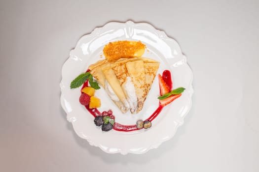 Isolated image of a gourmet pancake on a white plate with red sauce and berries, perfect for food blogs or recipe websites.