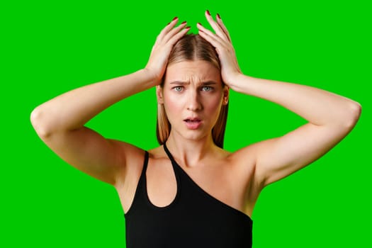 Young Woman Holding Hands Up to Head against green background in studio