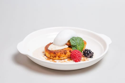 Gourmet cottage cheese pancakes with berries on white plate on white background. Delicious breakfast food.