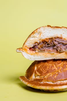 juicy burger cut with delicious filling on a yellow background.