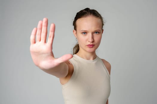 Young Woman Making Stop Sign With Hands on gray background in studio