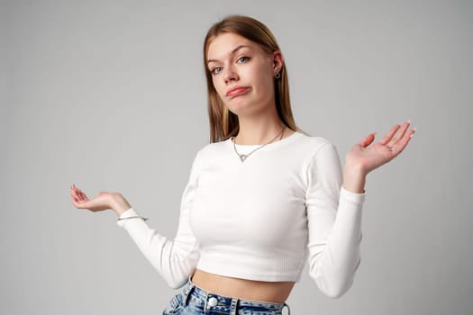 Young Woman in Blue Top Holding Out Hands in studio