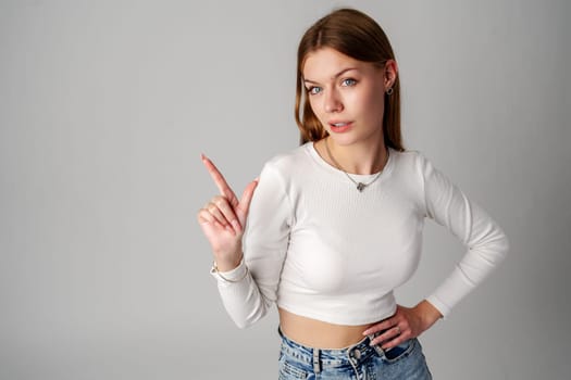 Young Woman Gesturing With Her Finger While Speaking Against a Gray Background close up