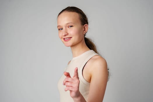 Young Woman in Tank Top Pointing at Camera in studio