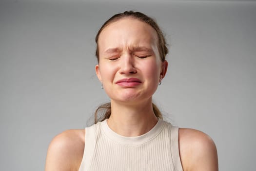 Young Woman Grimacing in Displeasure Against a Neutral Background in studio