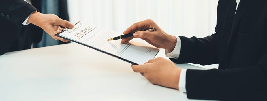 Business executive signing contract agreement document on the bale with the help from company attorney or lawyer service in law firm office. Business investing and finalizing legal processing. Shrewd