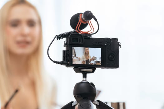 Blurred young woman making beauty and cosmetic tutorial video content for social media. Focused camera screen with beauty influencer showing how to apply beauty care to audience or followers. Blithe