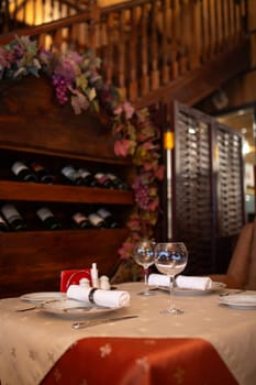 The image shows an elegant restaurant table setting with wine glasses and a bottle on the table with a blurred background of the restaurant.