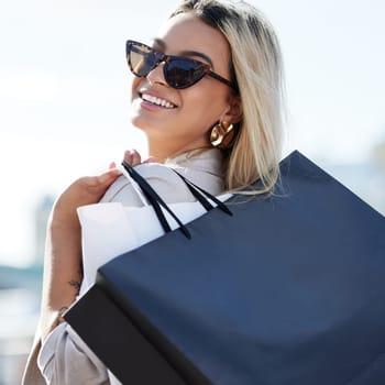 Woman, shopping bags and smile with sunglasses in portrait with retail therapy for purchase with buying. Consumerism, confidence and happiness with relax on weekend in city with pride for spending.