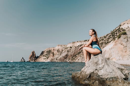 Woman beach vacation photo. A happy tourist in a blue bikini enjoying the scenic view of the sea and volcanic mountains while taking pictures to capture the memories of her travel adventure