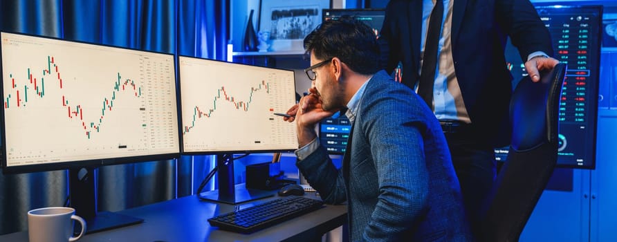 Stock exchange traders looking on high profit chart investment in panorama view, analyzing on monitor at night. Concept of discussing financial technology growth in neon light at workplace. Sellable.