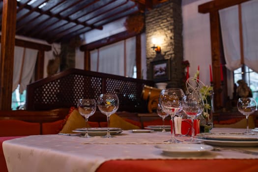 The image shows an elegant restaurant table setting with wine glasses and a bottle on the table with a blurred background of the restaurant.