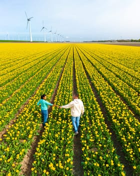 Men and women in tulip flower fields seen from above with a drone in the Netherlands, Tulip fields in the Netherlands during Spring, diverse couple in spring flower field