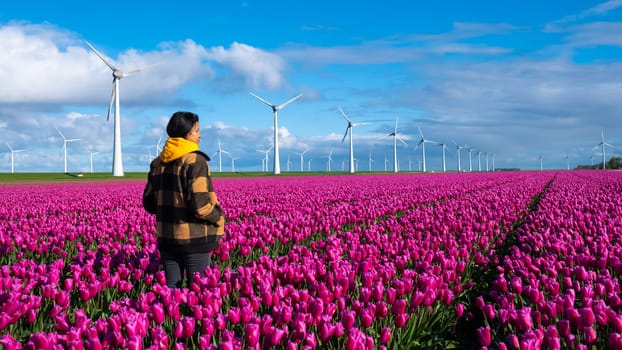 A woman stands gracefully in a sea of purple tulips, surrounded by the vibrant colors of spring in the Netherlands.