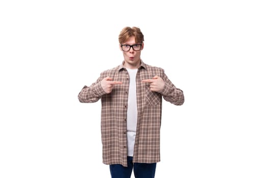 a young handsome red-haired guy in a plaid shirt is actively gesturing against the background with copy space.