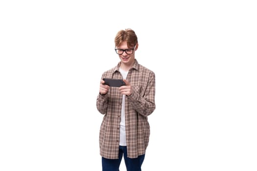 young european man with red short hair and glasses is watching video on the phone.