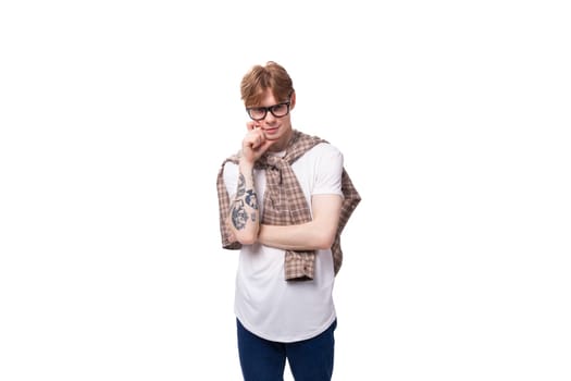 young pensive european red-haired guy in a t-shirt and shirt tied on his shoulders.