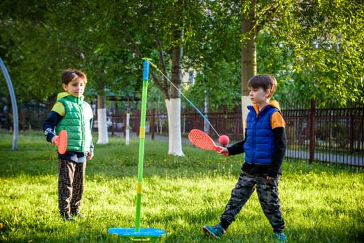 Two friends are playing tetherball swing ball game in summer camping. Two boy brother happy leisure healthy active time outdoors concept.