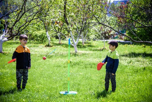 Two friends are playing tetherball swing ball game in summer camping. Two boy brother happy leisure healthy active time outdoors concept.