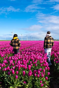 Two people standing joyfully in a field of vibrant purple tulips, surrounded by the beauty of Spring in the Netherlands.