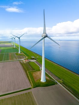 A wind farm comprised of towering turbines stands gracefully in the middle of a vast body of water, a serene and sustainable sight in the Netherlands in Spring. row of windmill turbines in Flevoland