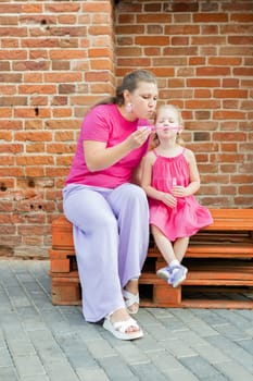 Deaf child with cochlear implant for hearing audio and aid for impairment having fun and laughs with mother outdoor in summer. Sound fitting device to help with communication listening and interaction.