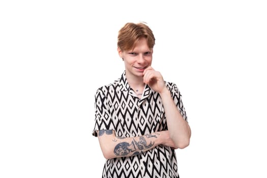 young stylish man with red hair is dressed in a short-sleeved shirt with a diamond pattern.