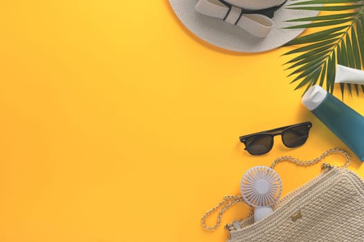 Traveler accessories with straw hat, sunglasses and fan on yellow background. Summer and travel concept.