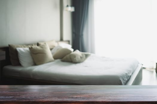Empty wooden table top and blurred cozy bedroom interior. For your design content or product.