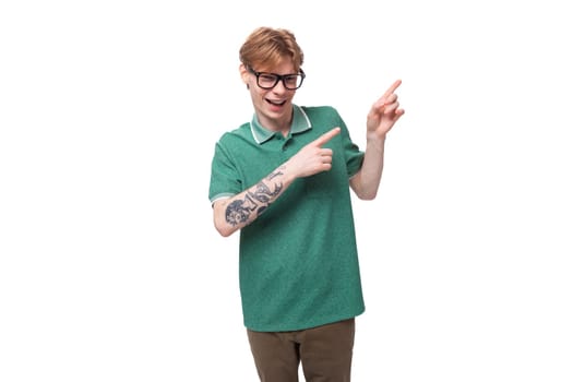 young surprised man with red hair in a green t-shirt on a white background with copy space.