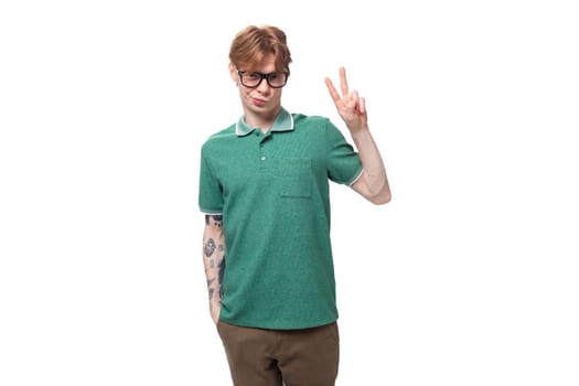young stylish cheerful european guy with red hair with a tattoo on his forearm wears a green t-shirt.