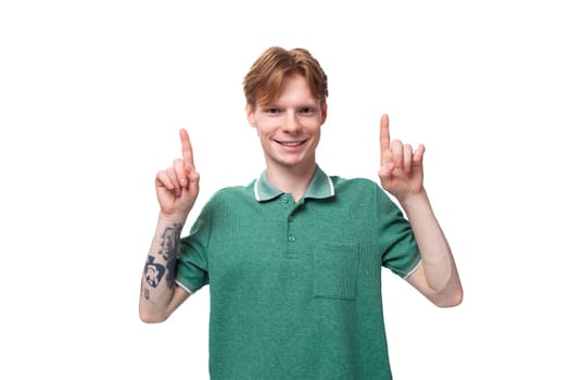 a young smart european guy with red hair with a tattoo on his forearm wears a green t-shirt has an idea and wants to tell it.