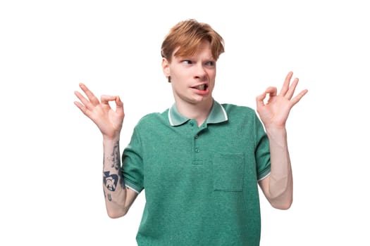 young caucasian man with red hair dressed in a green t-shirt takes off having doubts.