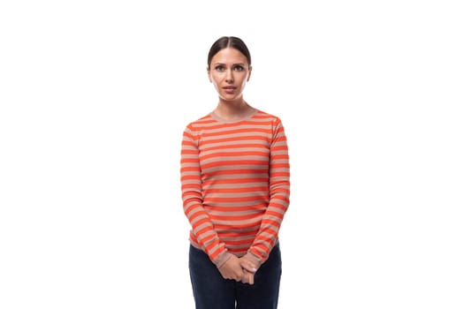 Young attentive slender brunette woman dressed in a striped orange jacket and jeans thought.