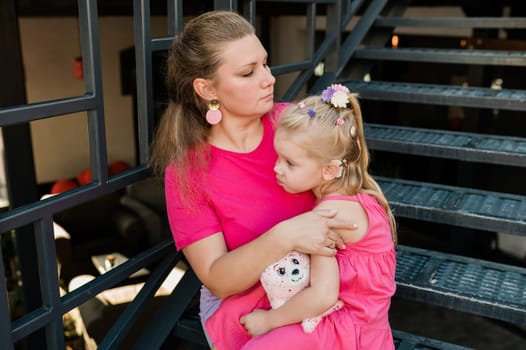 Mother holds and have fun her child with hearing aids and cochlear implants summer outdoor . Deaf and health concept. Diversity and inclusion. Copy space.