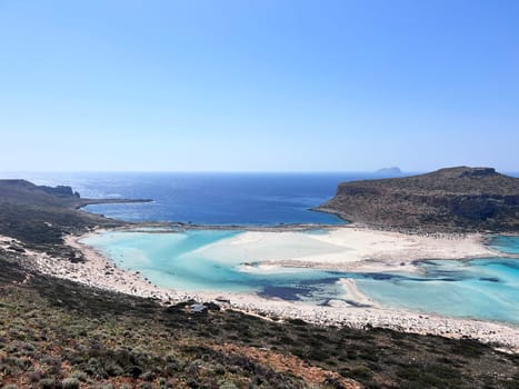 Balos lagoon on Crete island, Greece. Tourists relax and bath in crystal clear water of Balos beach. High quality photo