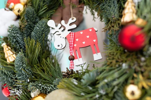 A close-up view of a festive Christmas wreath adorned with a charming reindeer ornament, showcasing traditional holiday decorations.