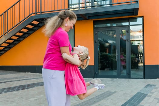 Mother holds and have fun her child with hearing aids and cochlear implants summer outdoor . Deaf and health concept. Diversity and inclusion. Copy space.