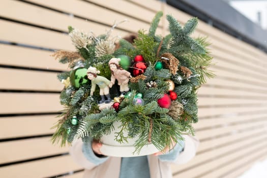 A close-up view of a potted plant adorned with various ornaments such as ribbons, baubles, and miniature figurines. The plants lush green leaves contrast beautifully with the colorful decorations, creating a festive and decorative display.