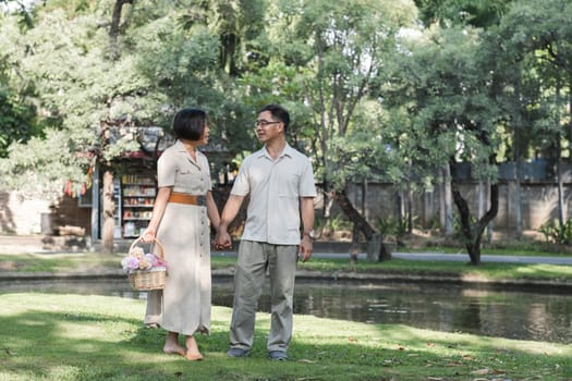 A retired couple walks outside together in the park on a relaxing vacation..