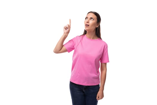 young beautiful model woman with straight black hair dressed in a pink t-shirt points her hand up.