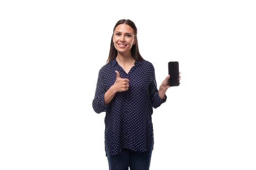 young european slender brunette woman in blue clothes advertises a smartphone with a mockup for advertising.